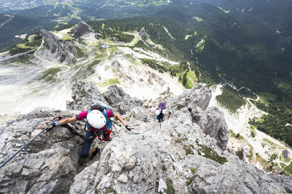 A climber along the via ferrata Olivieri on the Tofana di Mezzo with the Dolomiti Bellunesi National Park in the background, Belluno province, Veneto Italy