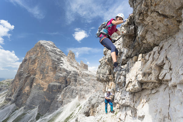 A climber along the via ferrata Olivieri on the Tofana di Mezzo with the Dolomiti Bellunesi National Park in the background, Belluno province, Veneto Italy