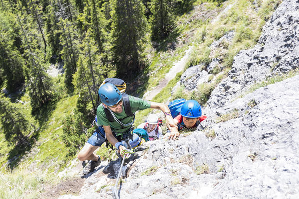 a kid and his father climbing the via ferrata (iron path) Les Cordes in the Dolomites, Bolzano province, South Tyrol, Trentino Alto Adige, Italy