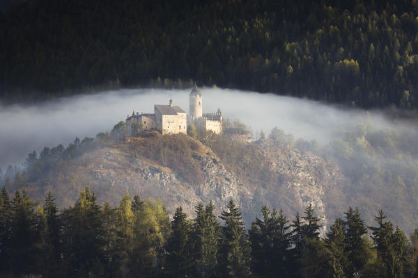 an autumnal view of Sprechenstein Castle (Castel Pietra) surrounded by the mist; Southern Wipptal, Bolzano province, South Tyrol, Italy, Europe, Trentino Alto Adige