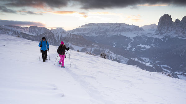a couple of tourists in a early morning winter trekking in Val Gardena, Bolzano province, South Tyrol, Trentino Alto Adige, Italy, Europe