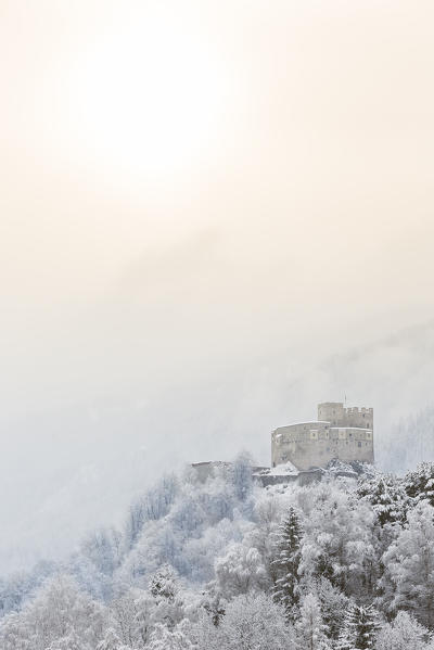a suggestive winter view of the castle of St. Michael in Bruneck with the first sun going out the mist, Bolzano province, South Tyrol, Trentino Alto Adige, Italy, Europe