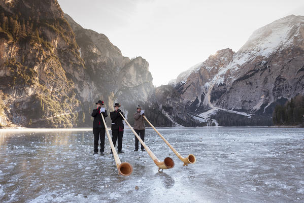 three horn players are playing onto the iced Pragsee during the Christmas time, Bolzano province, South Tyrol, Trentino Alto Adige, Italy, Europe