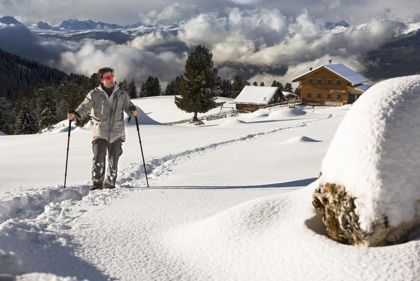 a hiker with snowshoe walking in the fresh snow, along the Adolf Munkel Weg, one of the most beautiful route in Villnössertal, Bolzano province, Trentino Alto Adige, South Tyrol, Italy, Europe.