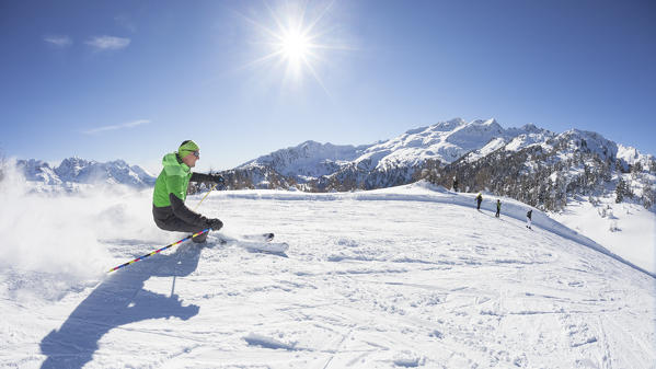 a skier is skiing along the slopes in the Folgarida ski resort with Brenta Group in the background, Trento province, Trentino Alto Adige, Italy, Europe
