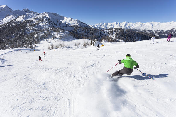 a skier is skiing along the slopes in the Folgarida ski resort with Adamello Group in the background. Trento province, Trentino Alto Adige, Italy, Europe