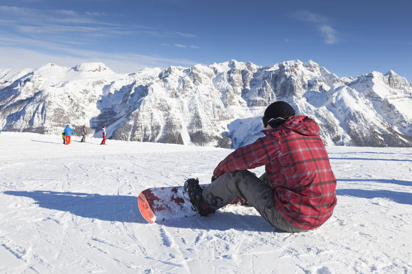 a snowboarder is sitting down on the snow looking toward the Brenta Group, Trento province, Trentino Alto Adige, Italy, Europe