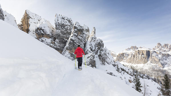 a view of a hiker with snowshoes walking around the Cinque Torri, the famous dolomitic group, belluno province, veneto, italy, europe,