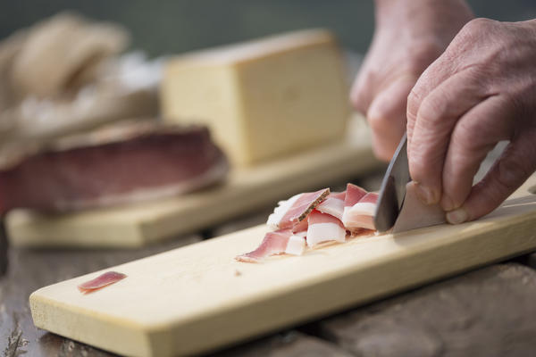 a chef is cutting a piece of Speck, (bacon), Bolzano province, South Tyrol, Trentino Alto Adige, Italy,