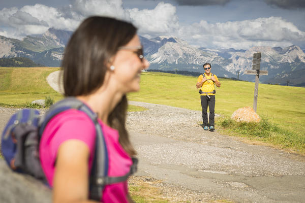 a couple of tourists are happy for their holidays on the Seiser Alm, (Alpe di Siusi), Bolzano province, South Tyrol, Trentino Alto Adige, Italy
