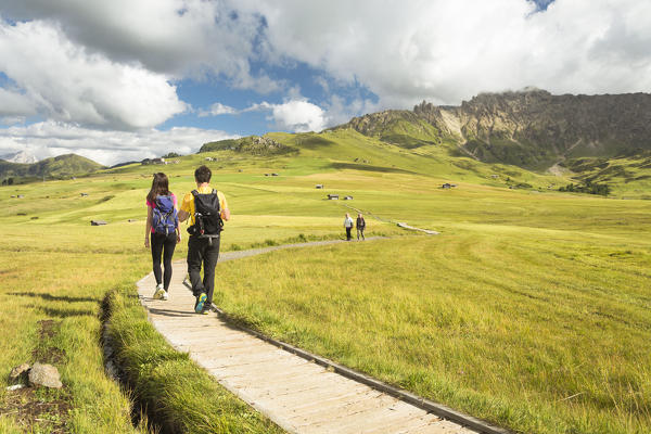 a couple of tourists is walking on the Seiser Alm, (Alpe di Siusi), Bolzano province, South Tyrol, Trentino Alto Adige, Italy