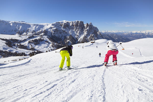 two skiers are skiing on the Seiser Alm with the Schlern in the background, Bolzano province, South Tyrol, Trentino Alto Adige, Italy