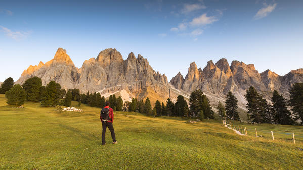 a hiker is looking at a beautiful sunset on the Geisler Group, Villnössertal, Bolzano province, South Tyrol, Trentino Alto Adige, Italy,