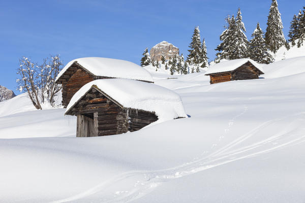 a view of three huts in a winter landscape in Val Badia, Bolzano province, South Tyrol, Trentino Alto Adige, Italy