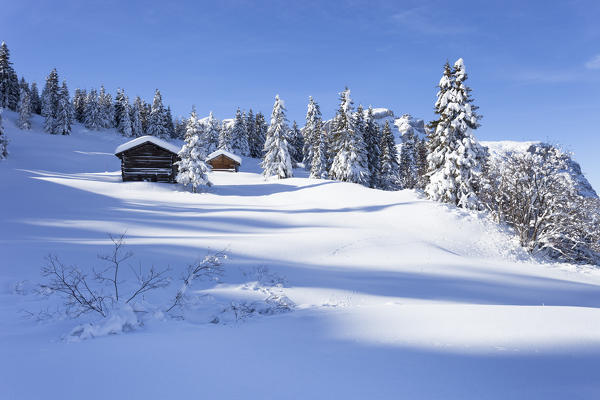 a winter view in Val Badia with two huts and the Sella Group in the background, Bolzano province, South Tyrol, Trentino Alto Adige, Italy