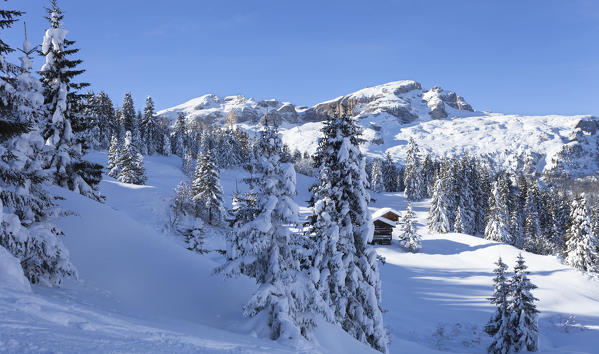 a winter view in Val Badia with two huts and the Sella Group in the background, Bolzano province, South Tyrol, Trentino Alto Adige, Italy