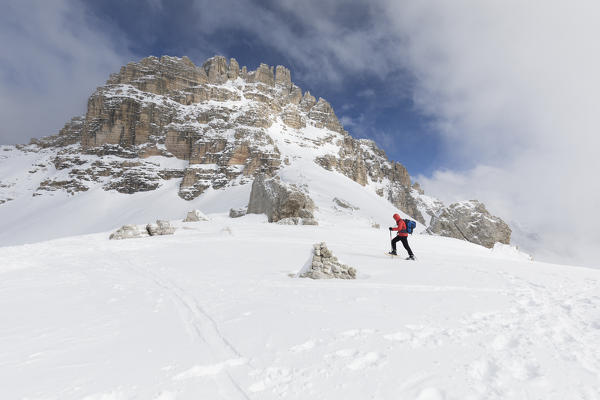 a hiker is walking with snowshoes under the Three Peaks of Lavaredo with Passportenkopf (Croda Passaporto) in the background, Bolzano province, South Tyrol, Trentino Alto Adige, Italy