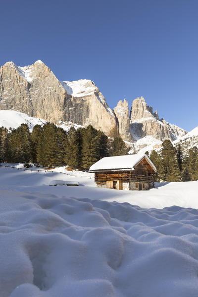 a winter landscape in Fassa Valley with the Rosengarten in the background and a little hut in the foreground, Trento province, Trentino Alto Adige, Italy