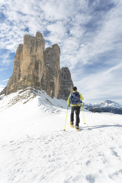 a hiker is walking with the snowshoes with the Three Peaks of Lavaredo in the background, Auronzo di Cadore, Belluno province, Veneto, Italy
