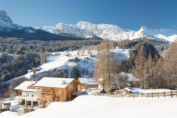 a winter landscape in Val Gardena with a typical wooden house and the Rosengarten Group in the background, Bolzano province, South Tyrol, Trentino Alto Adige, Italy 