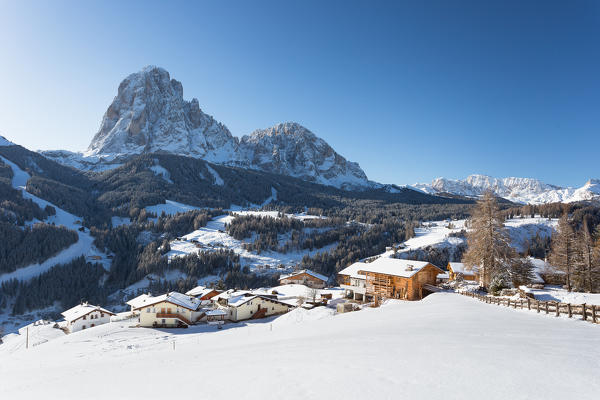 a winter landscape in Val Gardena with a little village in foreground and the Langkofel in the background, Bolzano province, South Tyrol, Trentino Alto Adige, Italy