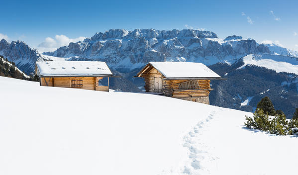 a view of two typical mountain huts in Val Gardena, with the Sella Group in the background, Bolzano province, South Tyrol, Trentino Alto Adige, Italy
