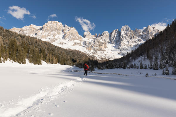 a hiker stands on the snow looking at the magnificent panorama in front of the Pala Group, Trento province, Trentino Alto Adige, Italy,