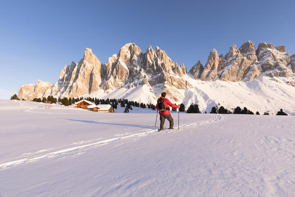 a beautiful winter sunset on the Geisler in Villnössertal with a hiker stunned in front of them, Bolzano province, South Tyrol, Trentino Alto Adige, Italy