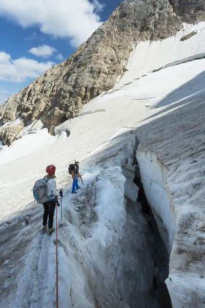 two hikers are walking on the glacier on the Marmolada, Trento province, Trentino Alto Adige, Italy