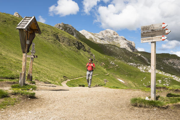A hiker during a trekking at Kreuzkofeljoch in Gadertal with Peitlerkofelgruppe in the background. Bolzano province, South Tyrol, Trentino Alto Adige, Italy (MR)