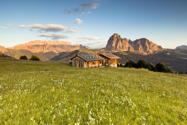 a view of an alpine hut during a sunset in Val Gardena with the Sella Group and the Langkofel in the background, Bolzano province, South Tyrol, Trentino Alto Adige, Italy