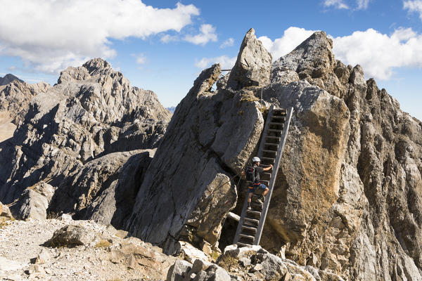 a climber is get on a stair along the ridge of the via ferrata Bepi Zac into the Marmolada Group and on the battlefront of the World War One, Trento Province, Trentino Alto Adige, Italy
