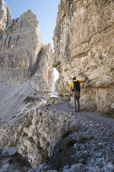 a hiker is walking along a ledge on the Paternkofel in the <Sextner Dolomites,  bolzano province, south tyrol, trentino alto adige, italy,