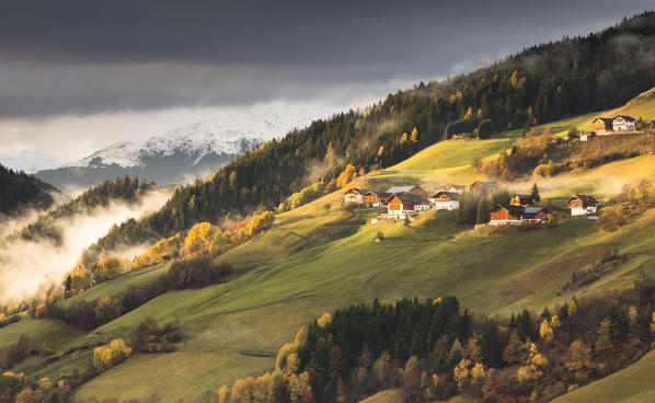 a view of an autumnal sunset in Villnössertal, with yellow trees and some alpine huts, Bolzano province, South Tyrol, Trentino Alto Adige, Italy