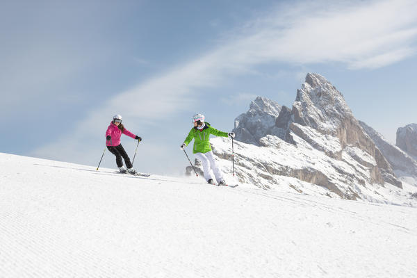 two skiers are skiing on the slopes in Val Gardena with the Geisler Group in the background, Bolzano province, South Tyrol, Trentino Alto Adige, Italy