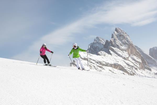 two skiers are skiing on the slopes in Val Gardena with the Geisler Group in the background, Bolzano province, South Tyrol, Trentino Alto Adige, Italy