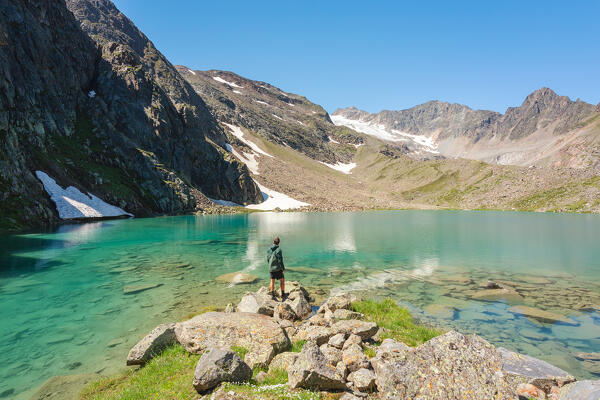 A Mountaineer staring at the turquoise waters of Blaue Lacke mountain lake with the glacier of Sulzenau in the background, Neustift im Stubaital, Innsbruck Land, Tyrol, Austria, Europe