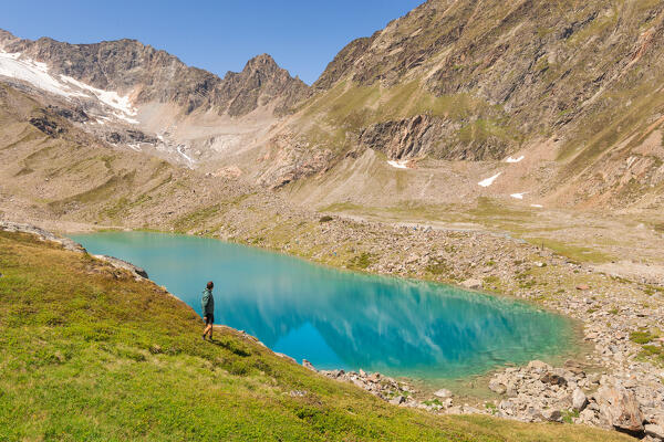 A mountaineer hiking around the Blaue Lacke mountain lake with Peiljoch and the Stubai Alps in the bacground, Neustift im Stubaital, Innsbruck Land, Tyrol, Austria, Europe