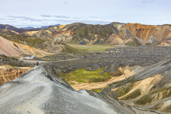 A trekker is looking at the Landmannalaugar panorama from Blahnukur mountain (Landmannalaugar, Fjallabak Nature Reserve, Highlands, Southern Region, Iceland, Europe)