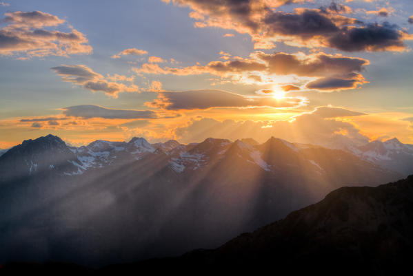 Plays of light at sunset through the clouds. Alps, Lombardy, Italy.