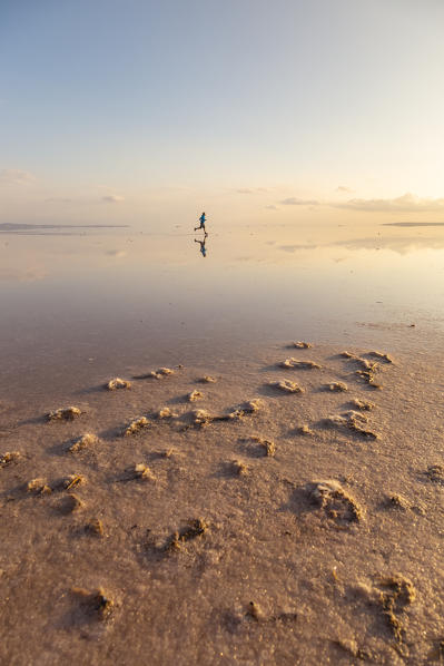 A runner in the shallow waters of the Tuz Golu salt lake at sunset. Sereflikochisar, Ankara district, central Anatolia, Turkey.