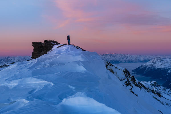 Alpinist in the summit of Sobretta mount at sunrise during winter season. Santa Caterina Valfurva, Sondrio district, Alps, Lombardy, Italy, Europe. 