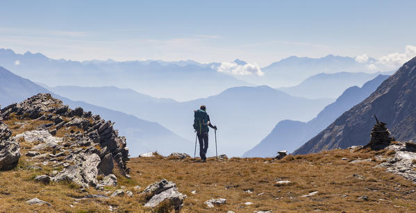 Hiker looking to the mountainscape and mountain profiles in background in Swiss Alps. Canfinal pass, Poschiavo, Valposchiavo valley, Grigioni canton, central Alps, Switzerland, Europe.