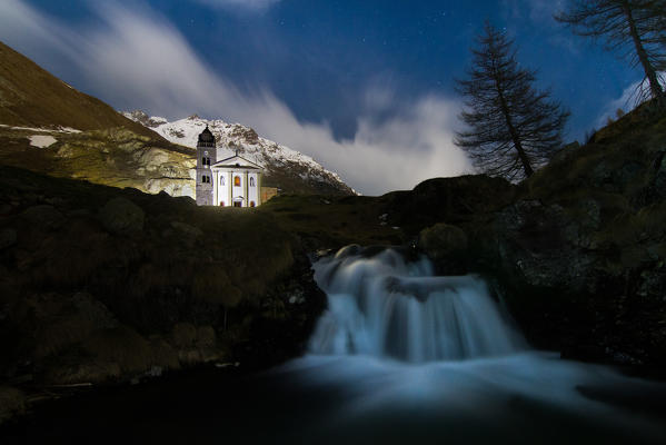 Alpine church in a full moon night. Valtellina, Lombardy, Italy