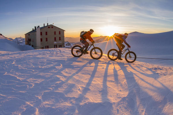 Casati refuge, Central Alps, Lombardy, Italy. Fat bikers in the Cevedale glacier at sunrise