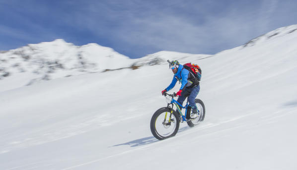 Snow, descend, fat bike. Fat bike in descend from Casati Refuge in Valfurva, Valtellina, Lombardy, Italy