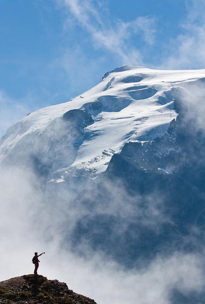 Trekkig at Stelvio pass, silhouette of an hiker facing the Ortles. Valtellina valley, Lombardy, Italy.