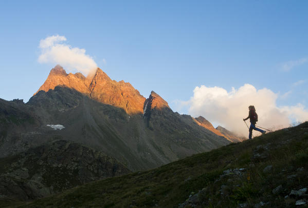 Europe, Italy, Lombardy, Sondrio. Trekker's silhouette at sunset in the mountains of Viola valley, Valtellina