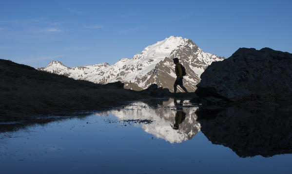 Europe, Italy, Lombardy. Trekking in the Alps, hiker in silhouette