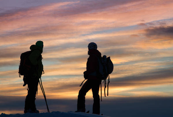 Europe, Italy, Lombardy. Two trekkers, in the sunset, after a journey spent on the mountains